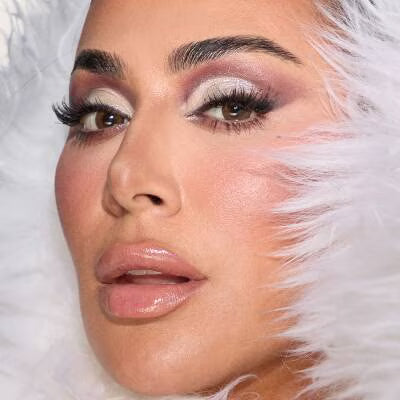 Close-up of a person with dramatic makeup and white feathers.