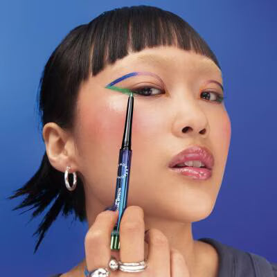 Person applying makeup with a brush against a blue background