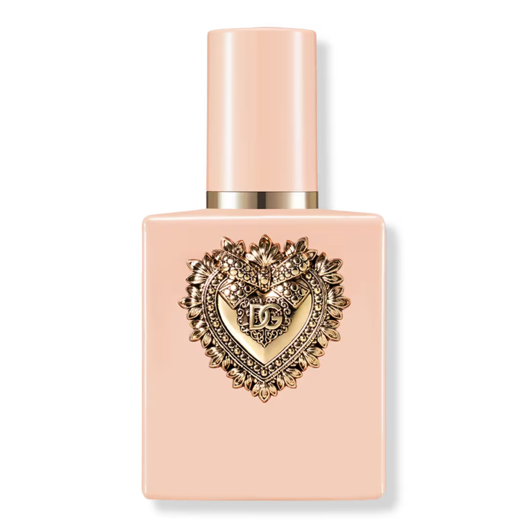Pink perfume bottle with decorative heart emblem on a white background