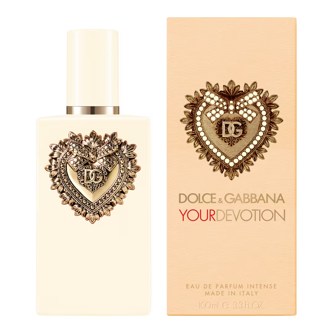 Dolce & Gabbana Your Devotion Eau de Parfum 100ml bottle next to its peach-colored packaging box, both featuring a heart-shaped crystal and gold-tone emblem on a white background.