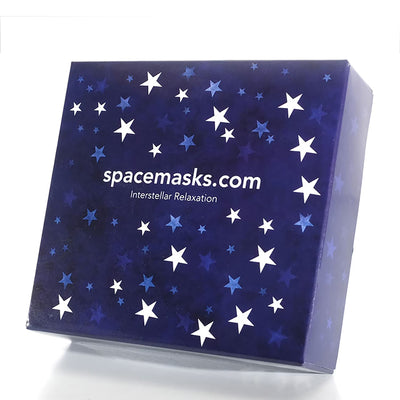 A square product box with a dark blue space-themed design featuring white and light blue stars, with the text 'spacemasks.com' and 'Interstellar Relaxation' printed on the front, set against a plain white background.