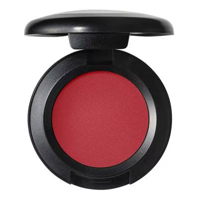 An open round makeup compact showing a vibrant red pressed powder, likely blush or eyeshadow, set in a matte black casing against a plain white background.