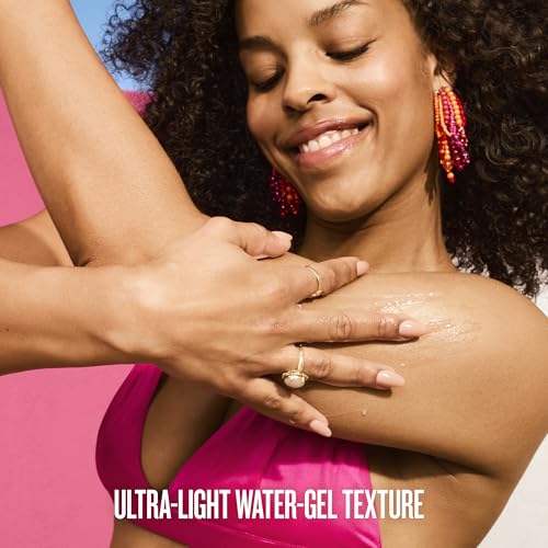 A close-up lifestyle shot of a woman with dark curly hair wearing a bright pink bikini top, with another person's hand applying a glossy, wet-looking gel to her shoulder. She is wearing colorful beaded earrings and gold rings.
