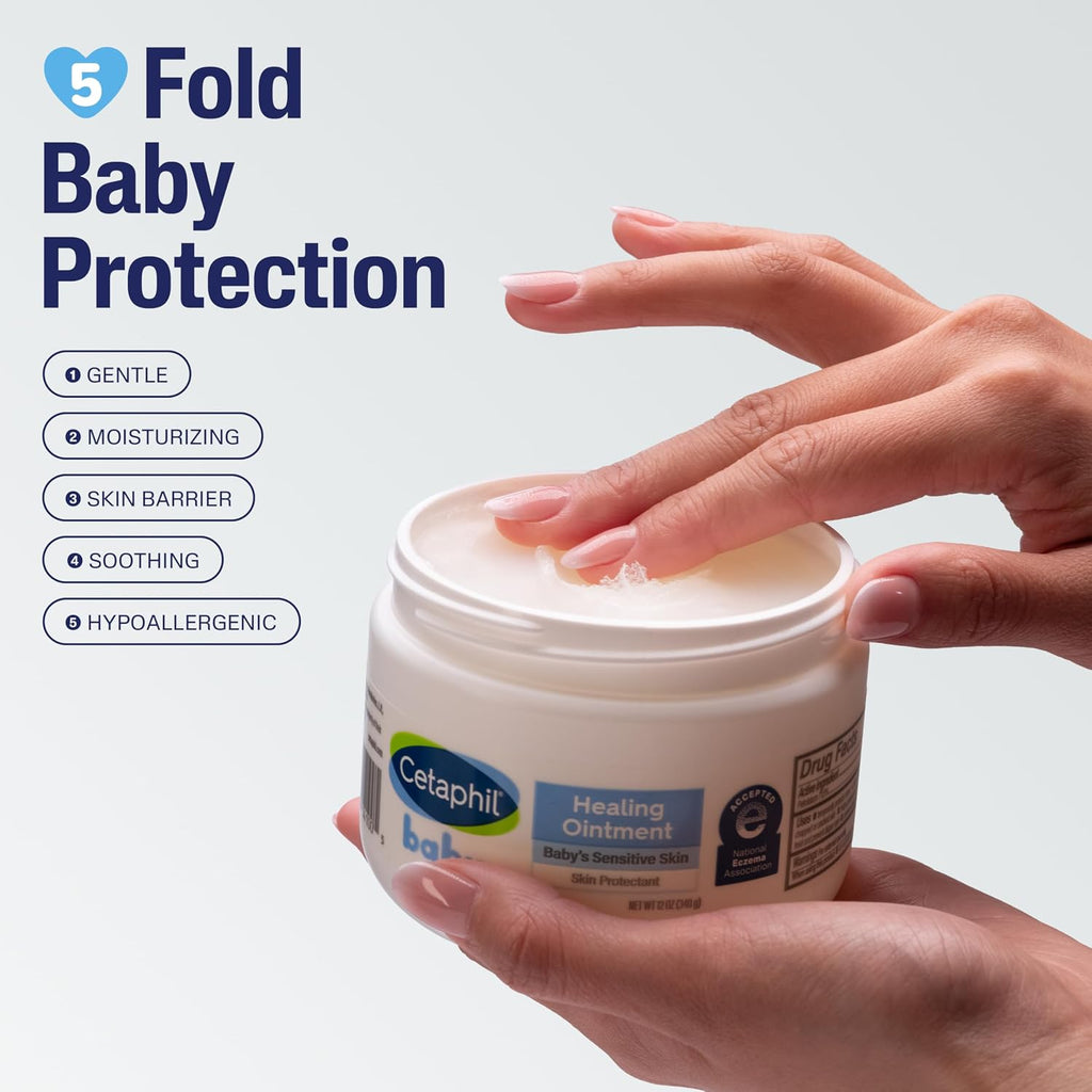 Cetaphil baby healing ointment jar with a hand holding it, on a light gray background.