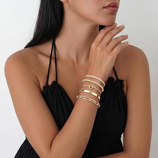 Woman wearing gold bracelets on a plain background
