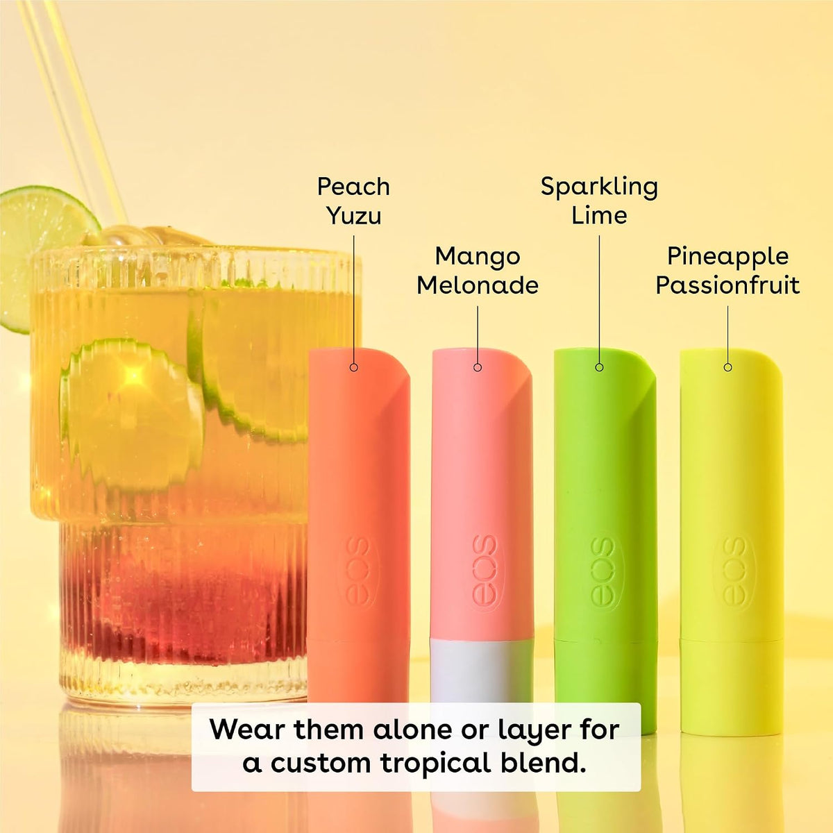 Four eos lip balms in peach, mango, sparkling lime, and pineapple passionfruit flavors next to a tropical drink.