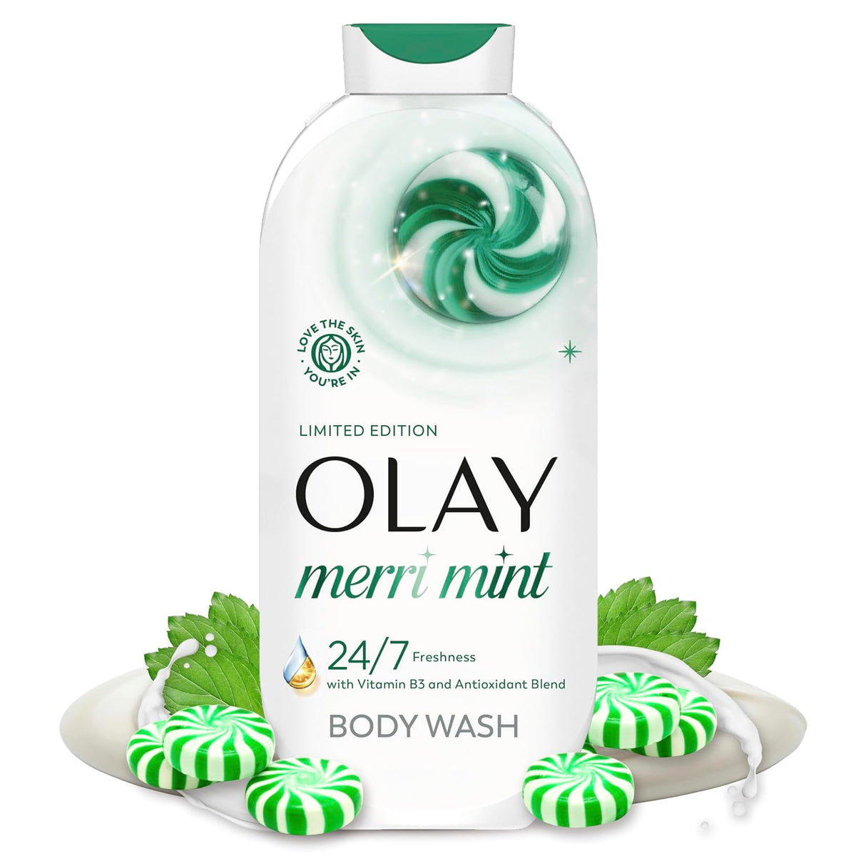 A bottle of Olay Merri Mint body wash centered on a white background, surrounded by mint leaves and green-and-white striped candy pieces on a plate. The bottle is white with green and black text and a green swirl graphic near the top.