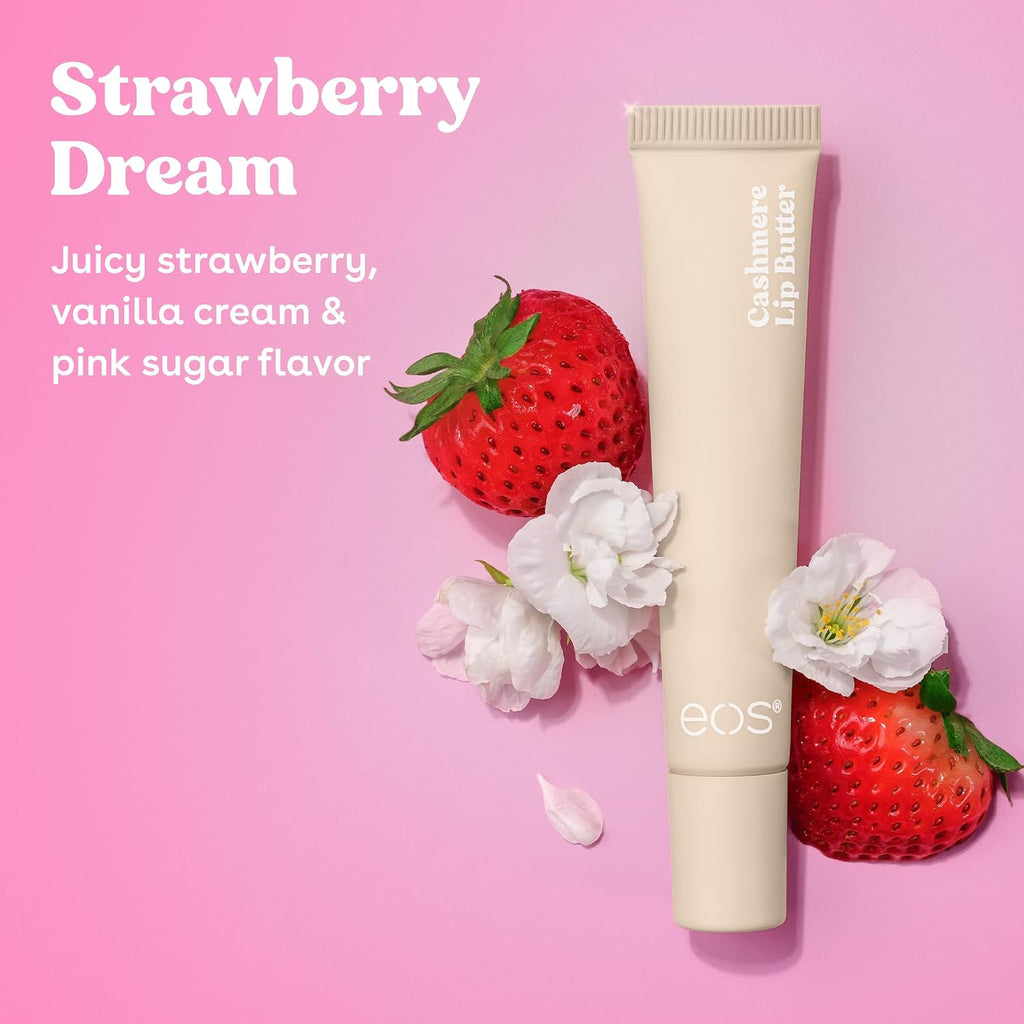 A beige squeeze tube of EOS Cashmere Lip Balm in the Strawberry Dream flavor, styled on a pink background with fresh strawberries, white blossoms, and a small petal. The text on the left reads 'Strawberry Dream' and 'Juicy strawberry, vanilla cream & pink sugar flavor'.