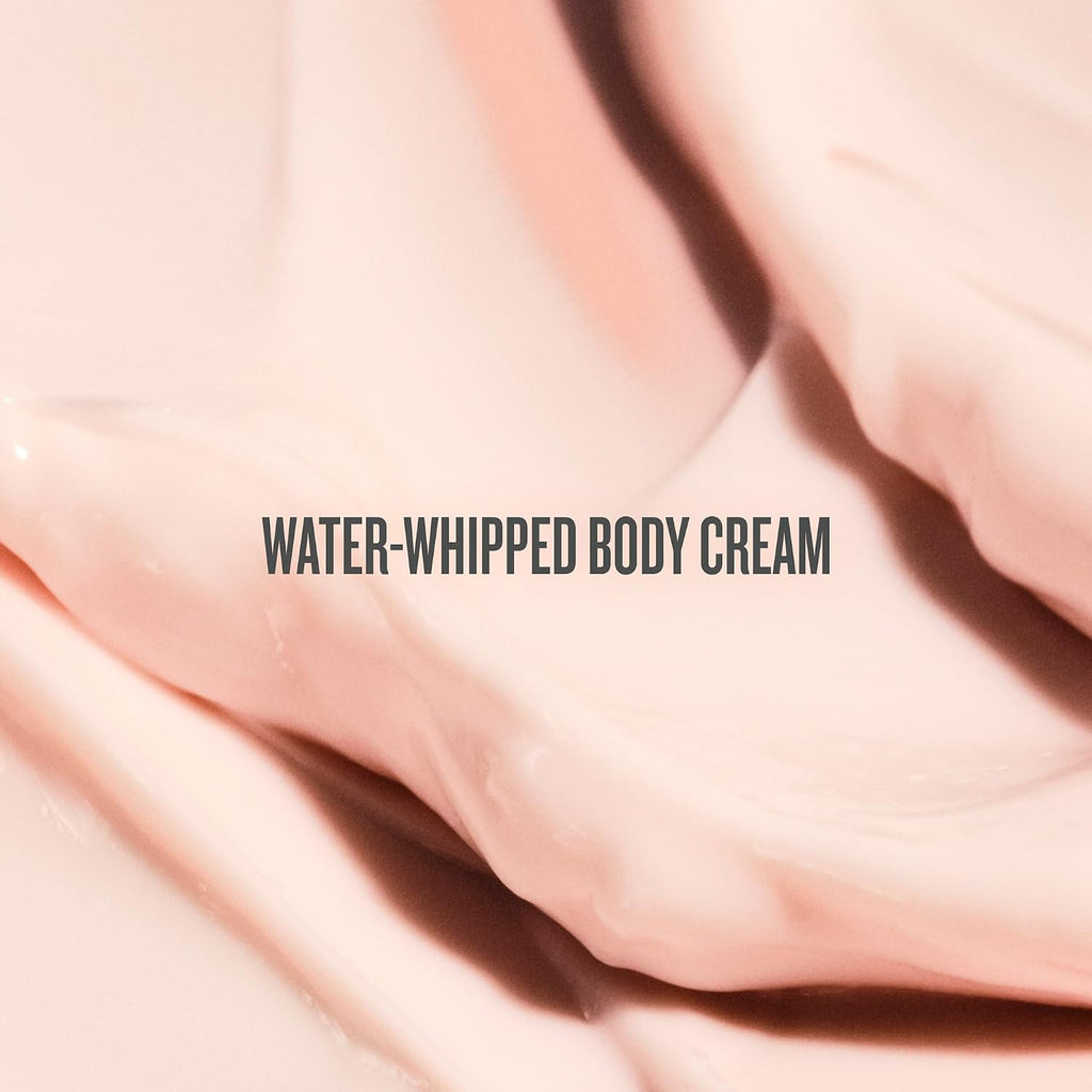 Close-up of water-whipped body cream with a soft pink background