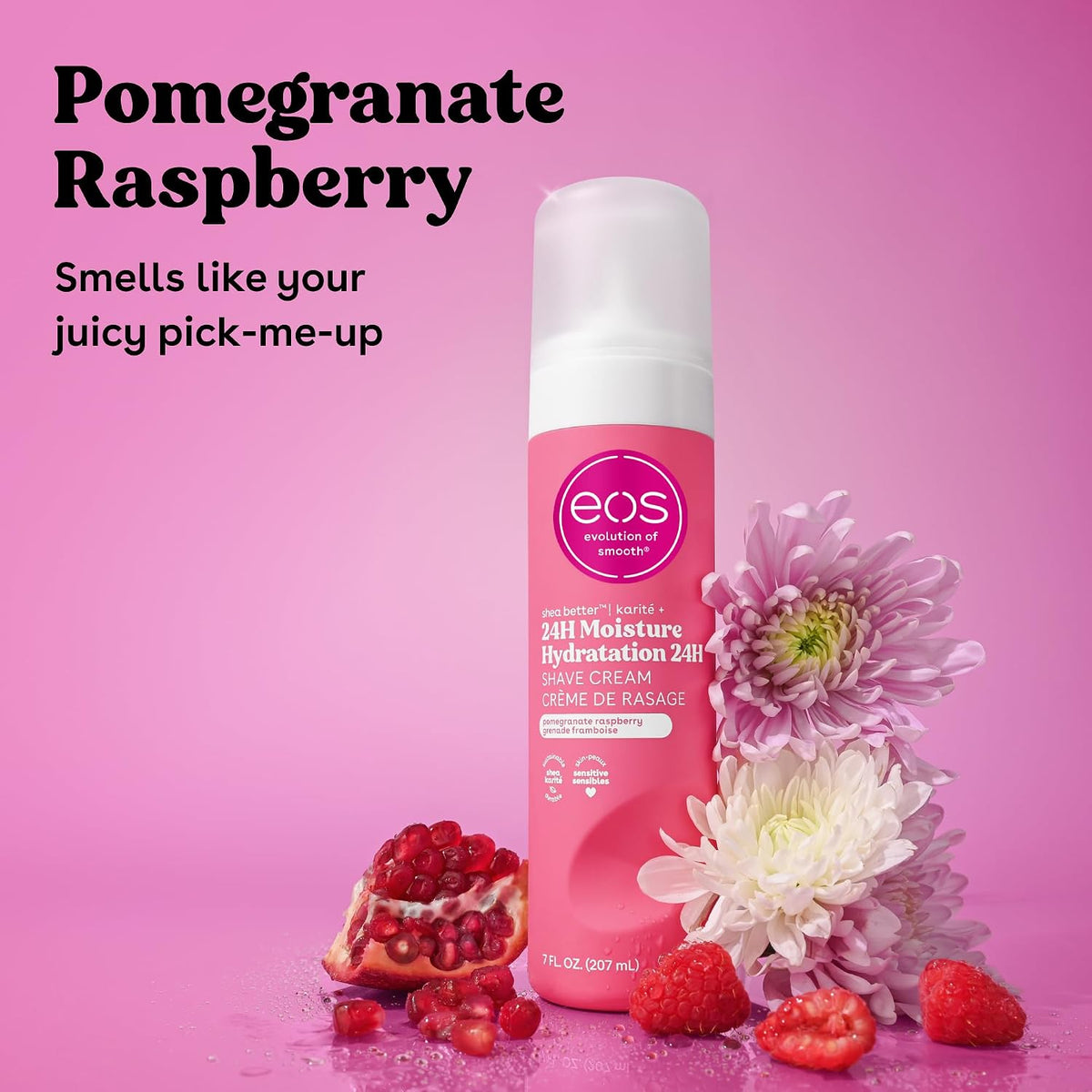 A pink EOS Cosmetics Save Cream bottle labeled 'Pomegranate Raspberry' stands on a pink background with decorative pomegranate, raspberries, and flowers around it. Large text at the top reads 'Pomegranate Raspberry' and 'Smells like your juicy pick-me-up'.