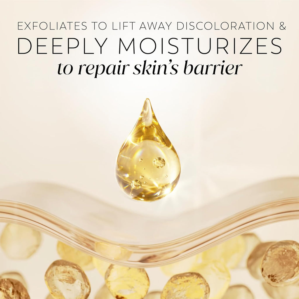A skincare promotional graphic with text reading 'EXFOLIATES TO LIFT AWAY DISCOLORATION & DEEPLY MOISTURIZES to repair skin's barrier' above a clear teardrop-shaped droplet filled with golden serum, set over a glass bowl containing round golden exfoliating beads.