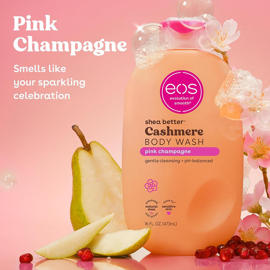 A bottle of EOS Cashmere Body Wash in Pink Champagne scent, styled with a fresh pear, pomegranate seeds, and pink blossoms on a pink background with promotional text.