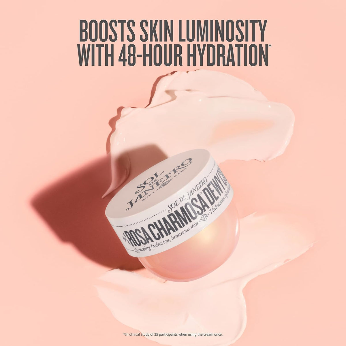 A jar of Sol de Janeiro Rosa Charming Dewy Moisturizer sits on a pink background with a cream-colored product smear behind it and marketing text at the top.
