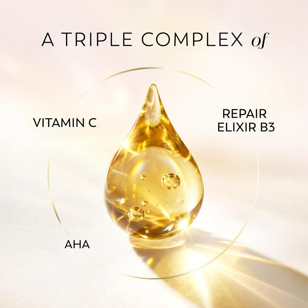 A golden teardrop-shaped droplet of serum or oil centered on a warm cream background, with text reading 'A TRIPLE COMPLEX of' and callouts 'VITAMIN C', 'REPAIR ELIXIR B3', and 'AHA'.
