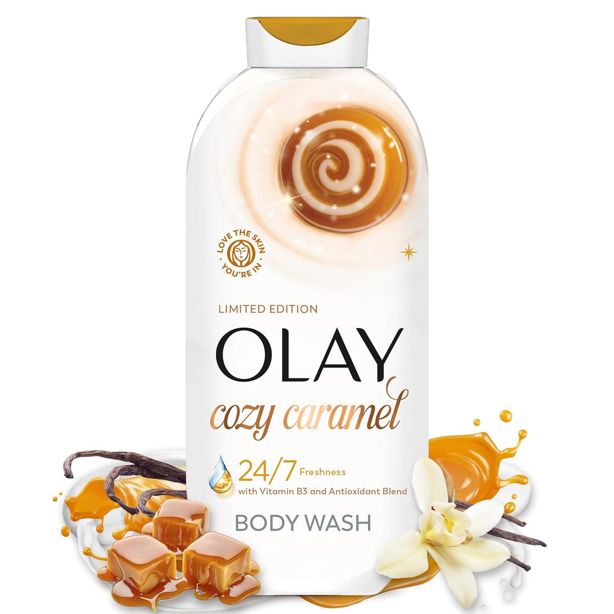 A bottle of Olay Cozy Caramel body wash centered on a white background, surrounded by caramel drizzle graphics, vanilla beans, and caramel cubes. The bottle is white with gold and black text, and the top cap has a gold accent.
