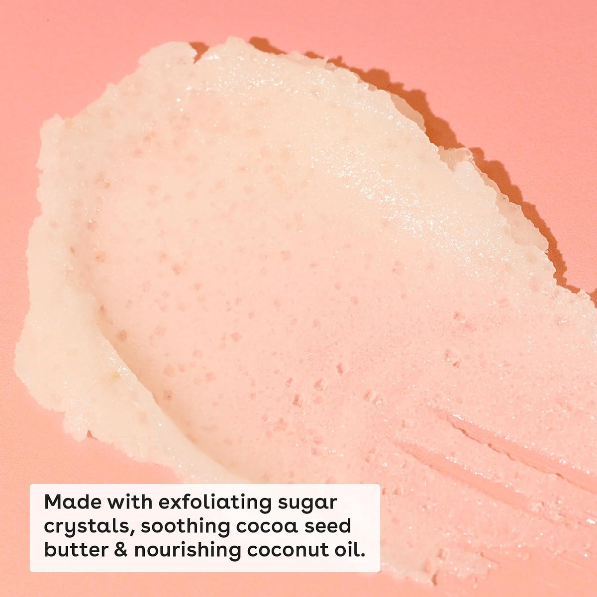 Close-up of a skincare product with exfoliating sugar crystals on a pink background