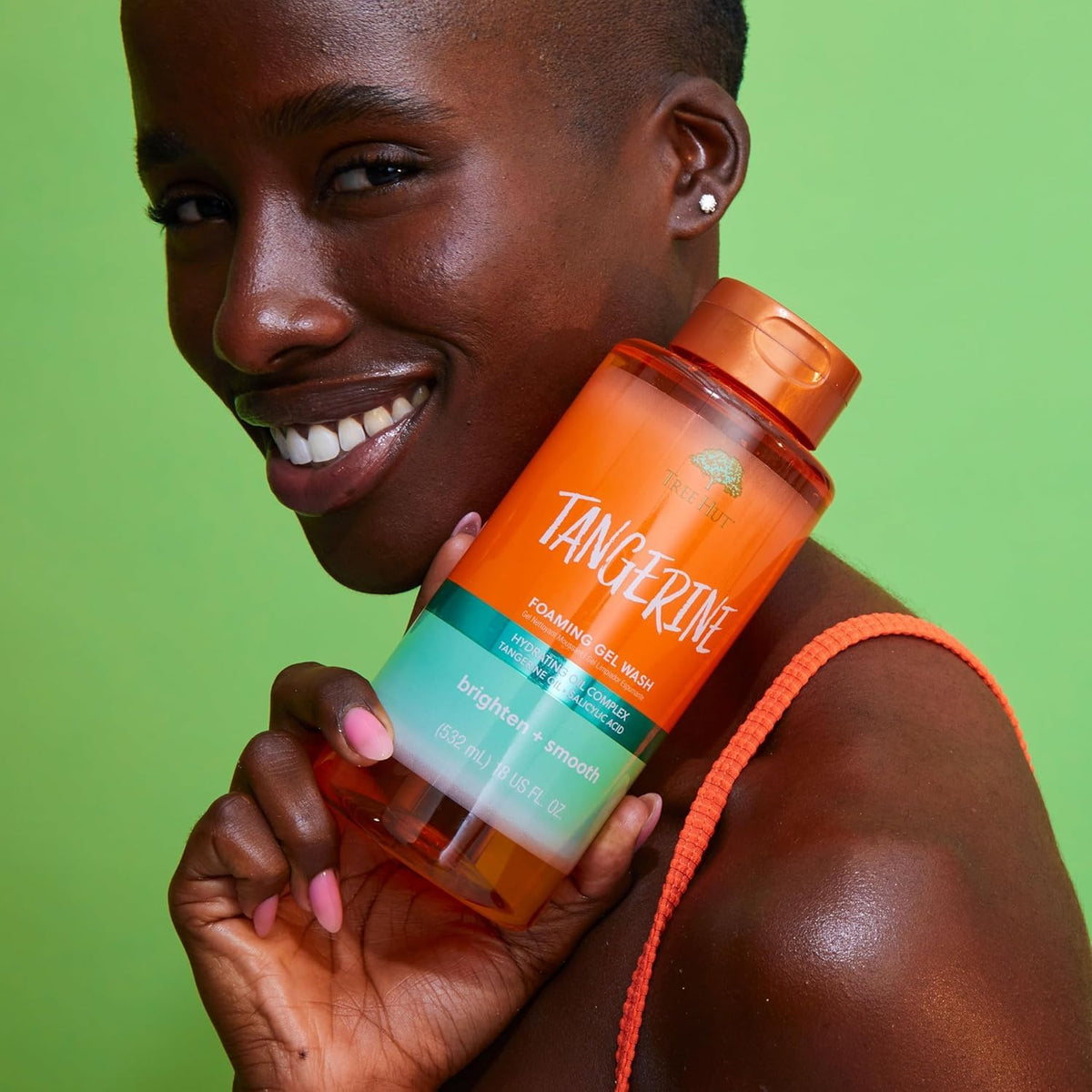 Person holding a Tangerine skincare product against a green background