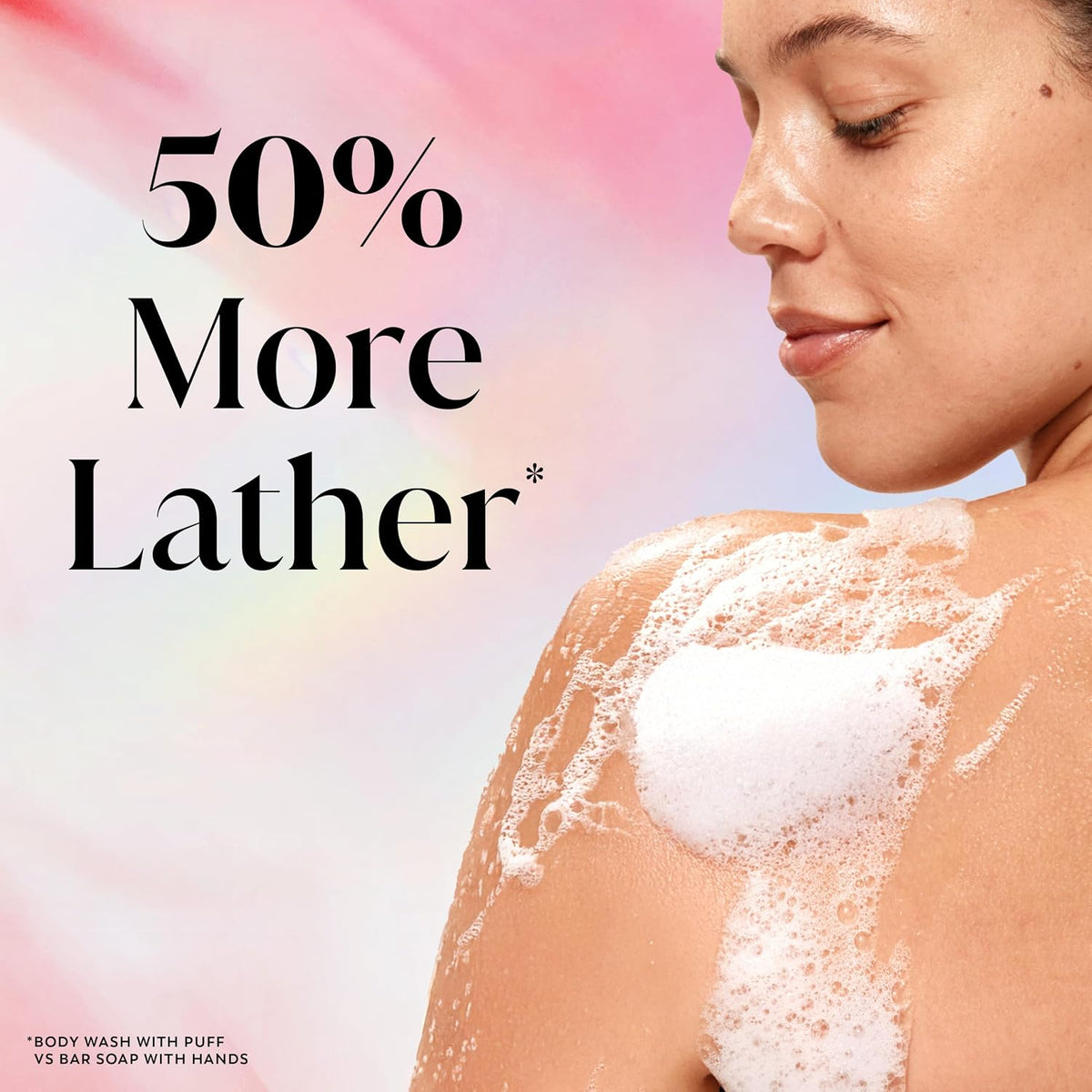 A woman in profile with white body foam on her shoulder against a soft pink and white background, with large text reading '50% More Lather'.