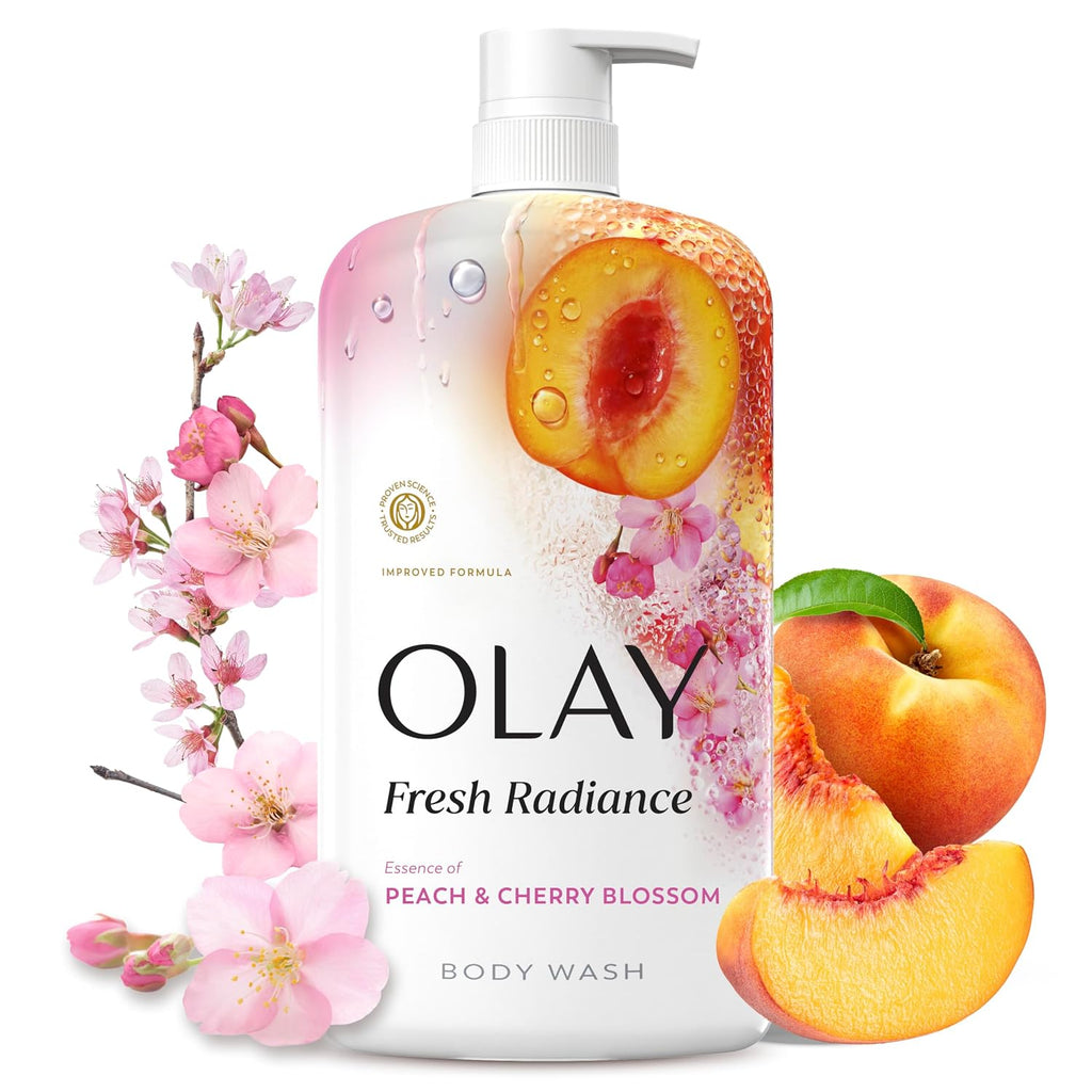 A bottle of Olay Fresh Radiance body wash with peach and cherry blossom graphics, shown with pink blossoms and whole peaches on a white background.