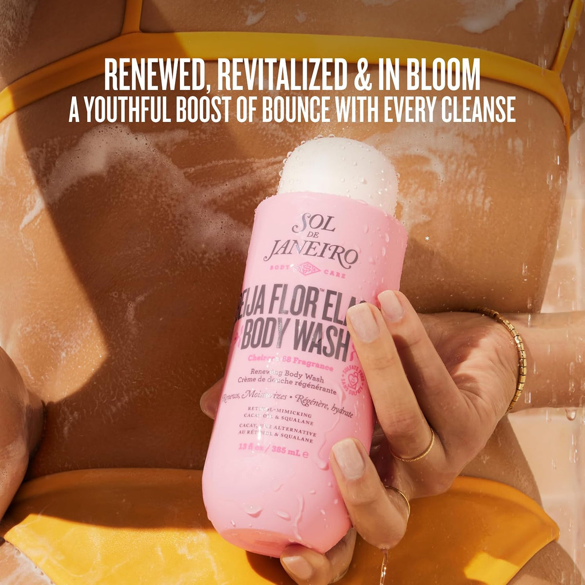 Person holding a pink bottle of Sol de Janeiro body wash under shower water.