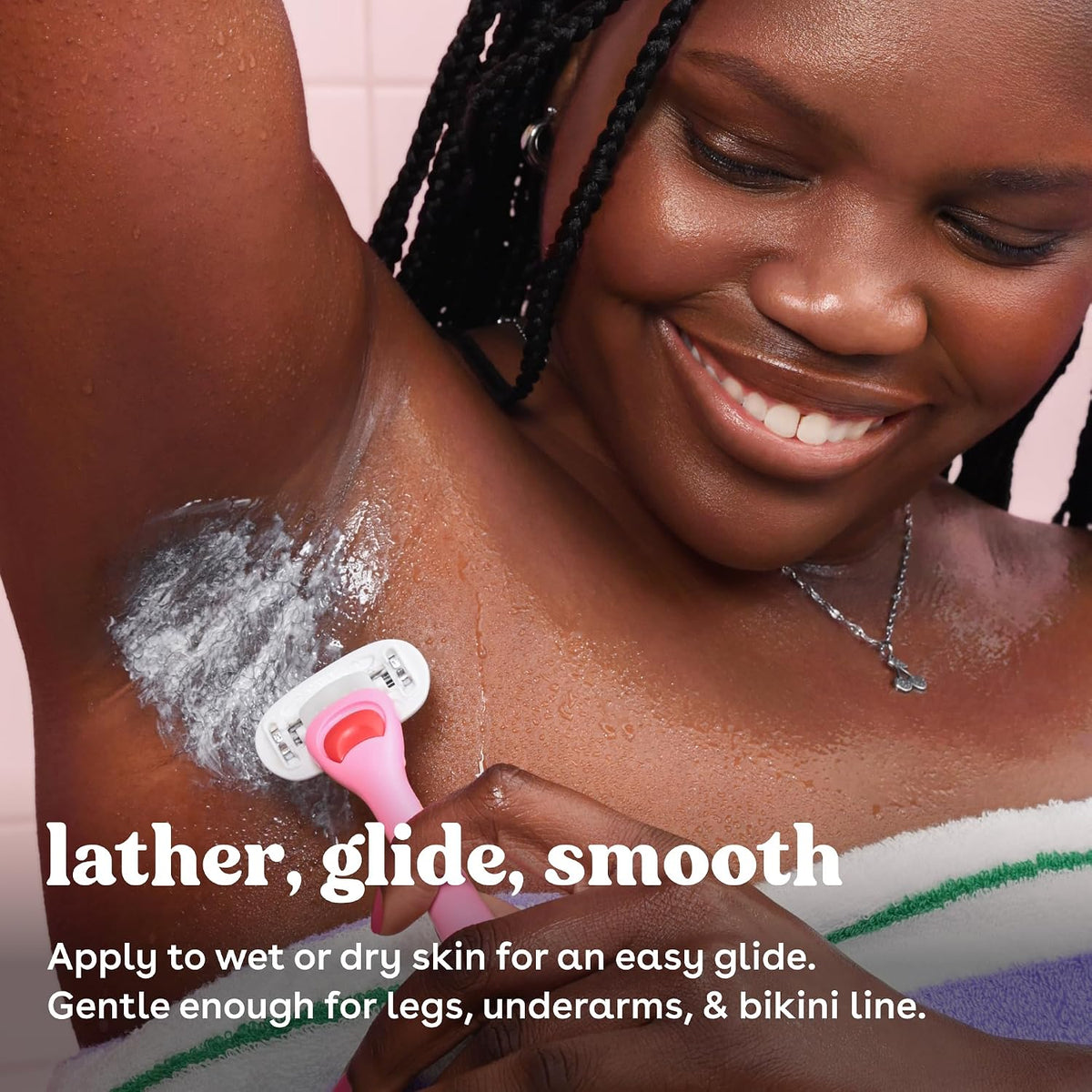 A close-up lifestyle shot of a woman shaving her underarm with a pink and white razor, showing white shaving lather. Text overlays read 'lather, glide, smooth' and 'Apply to wet or dry skin for an easy glide.