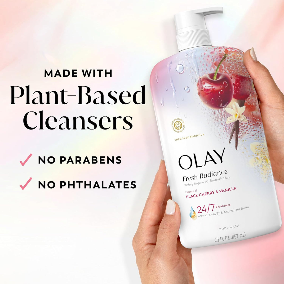 A hand holds an Olay Fresh Radiance body wash bottle against a soft pink and white background, with text on the left reading 'MADE WITH Plant-Based Cleansers' and 'NO PARABENS NO PHTHALATES'. The bottle is white with cherry and vanilla graphics.