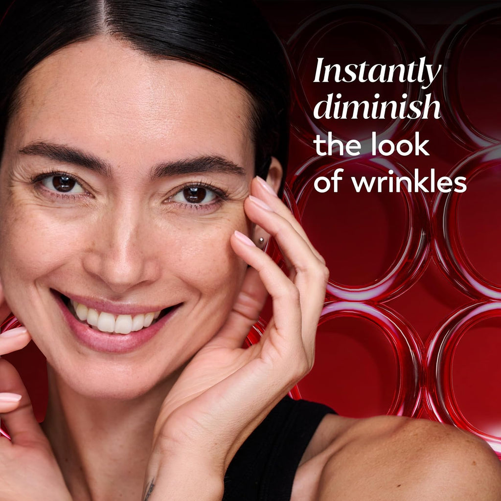 A close-up of a smiling woman with dark hair and hands near her face, set against a red background with circular patterns and the text 'Instantly diminish the look of wrinkles'.
