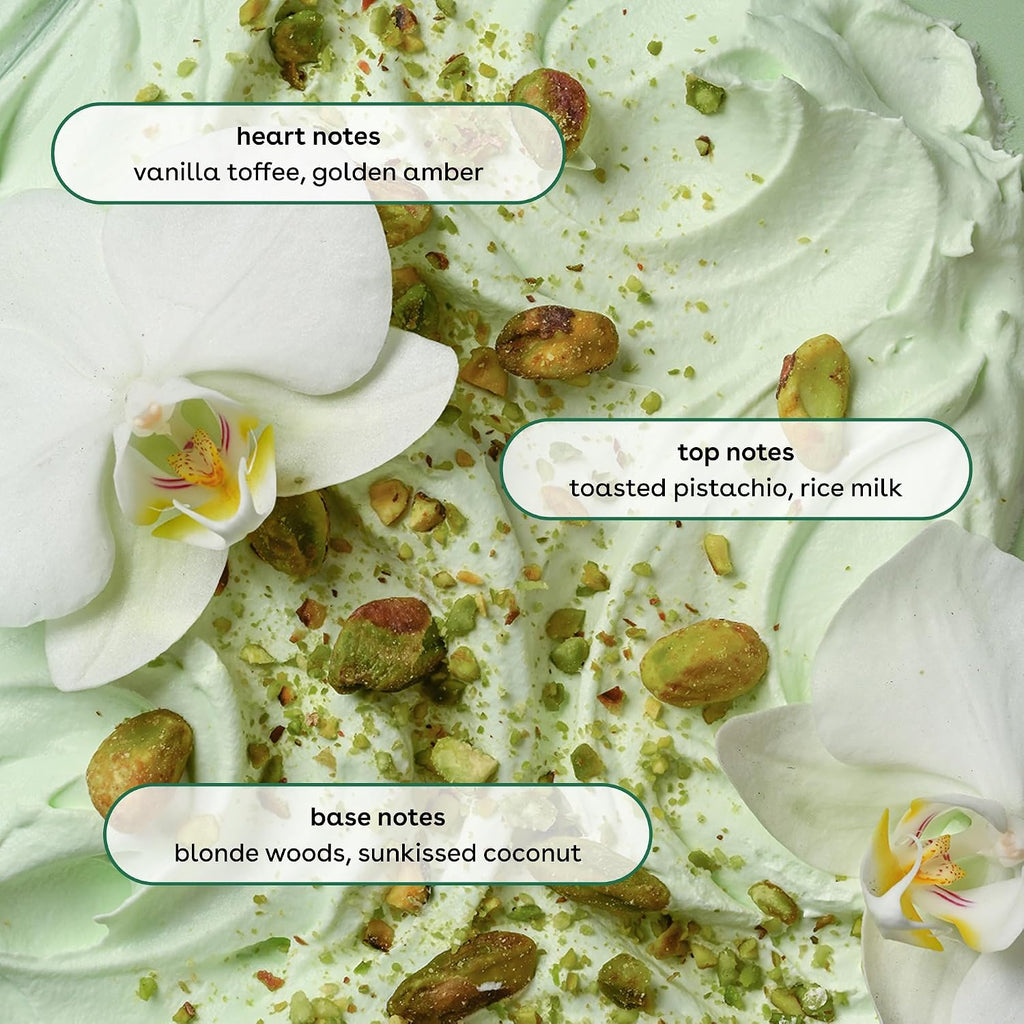 A close-up of a whipped cream or lotion texture in pale mint green, topped with chopped pistachios and overlaid with labeled scent notes: heart notes, top notes, and base notes. White orchid flowers are visible around the edges.