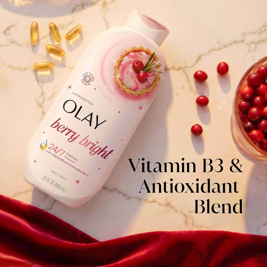 Olay Berry Bright Vitamin B3 & Antioxidant Blend body wash bottle on a white marble surface with scattered red cranberries, gold capsules, and a red velvet cloth. Text overlay reads 'Vitamin B3 & Antioxidant Blend'.