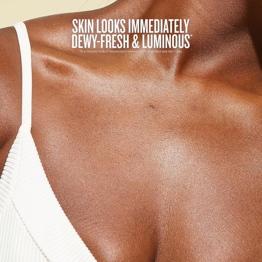 Close-up of a person's upper chest and shoulder wearing a white ribbed spaghetti-strap top, with text reading 'SKIN LOOKS IMMEDIATELY DEWY-FRESH & LUMINOUS'.