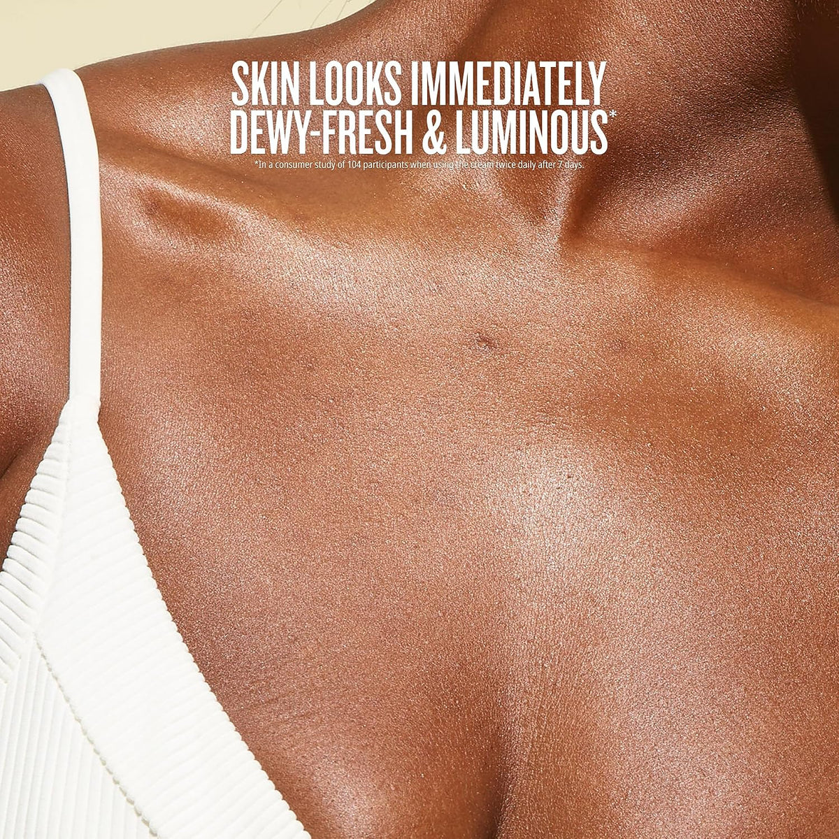 Close-up of a person's upper chest and shoulder wearing a white ribbed spaghetti-strap top, with text reading 'SKIN LOOKS IMMEDIATELY DEWY-FRESH & LUMINOUS'.