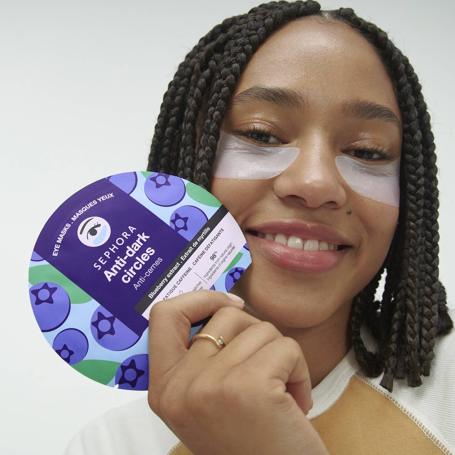 Woman holding a container of eye masks with a white background