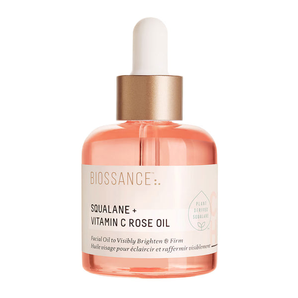 Biosance Squalane + Vitamin C Rose Oil facial oil in a clear glass bottle with a white dropper cap, a metallic gold collar, and rose pink oil inside, set against a plain white background.
