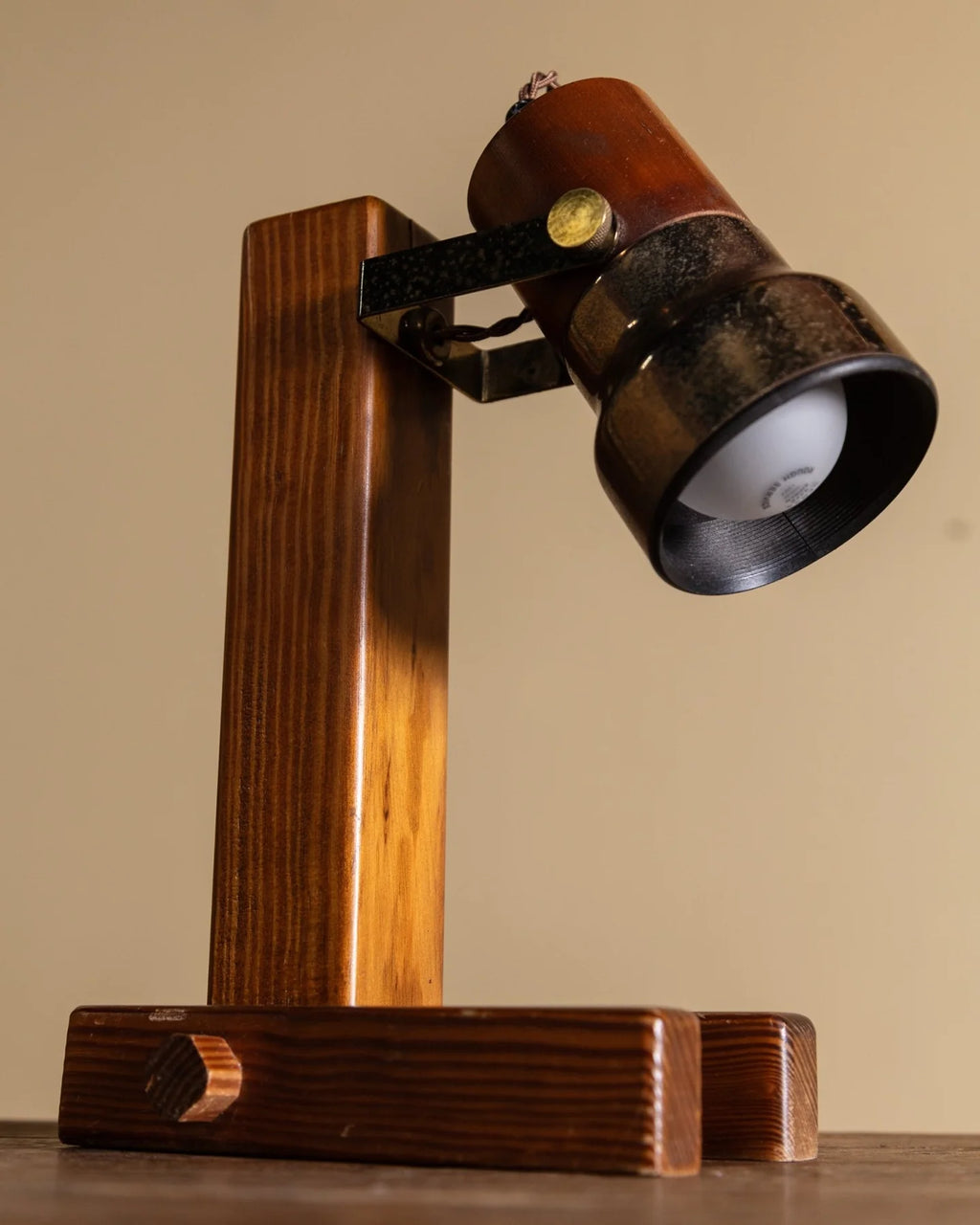 A vintage-style adjustable desk lamp with a dark brown wooden stand and a metal lamp head, shown against a plain beige background.
