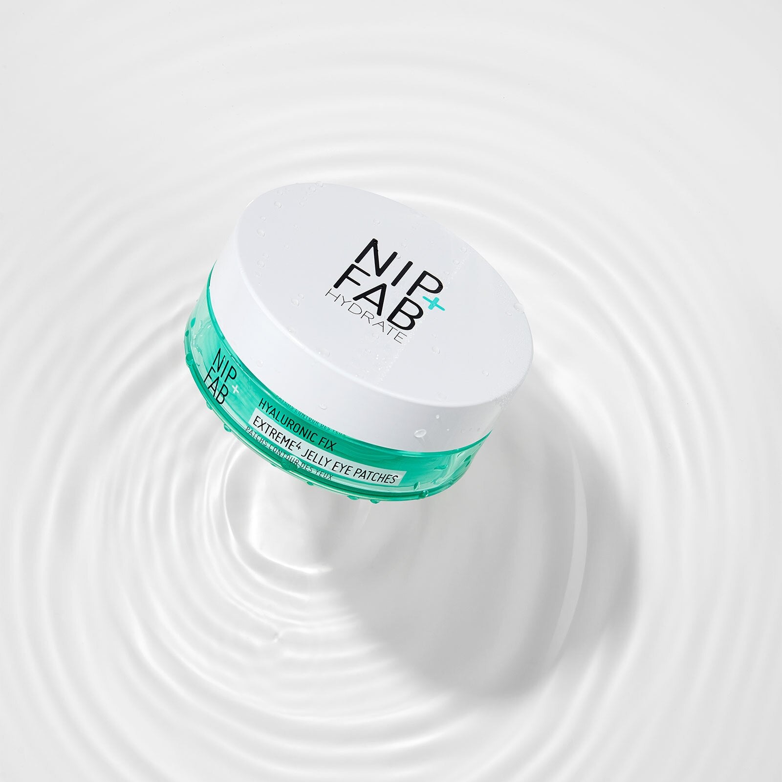A white cosmetic jar labeled NIPFAB HYDRATE Extreme Eye Parasols, featuring a teal band around the middle, set against a white background with water ripples.