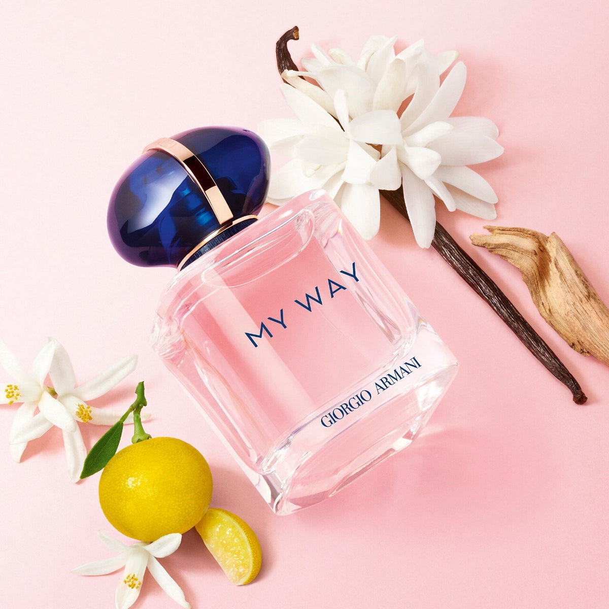 Perfume bottle labeled 'My Way' by Giorgio Armani with flowers and lemons on a pink background