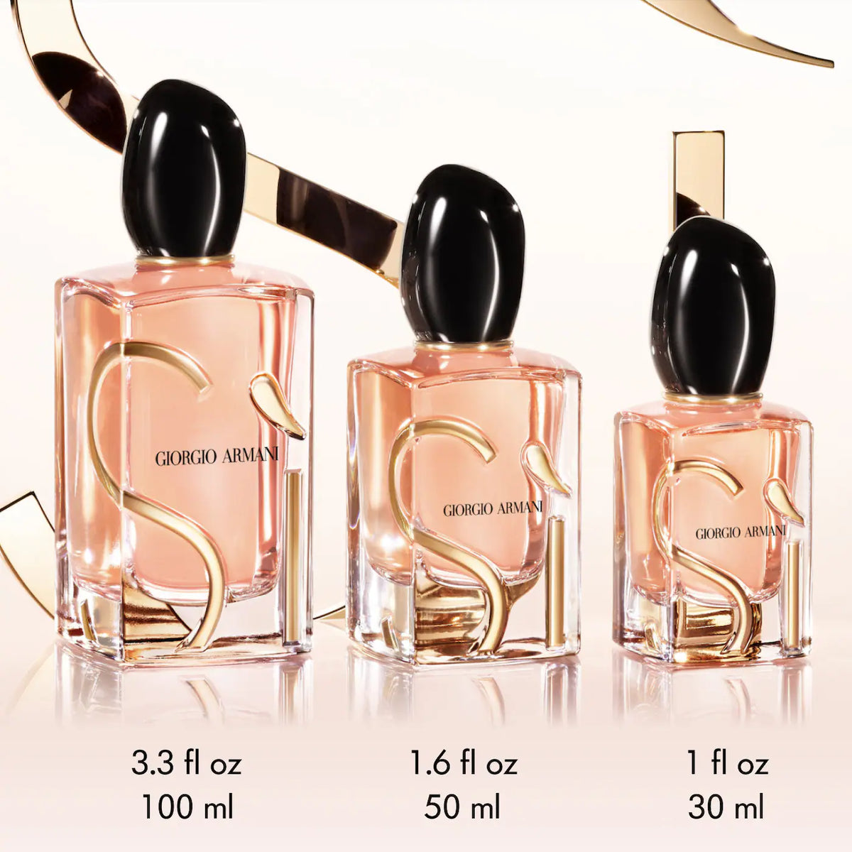 Three Giorgio Armani perfume bottles of different sizes on a reflective surface.