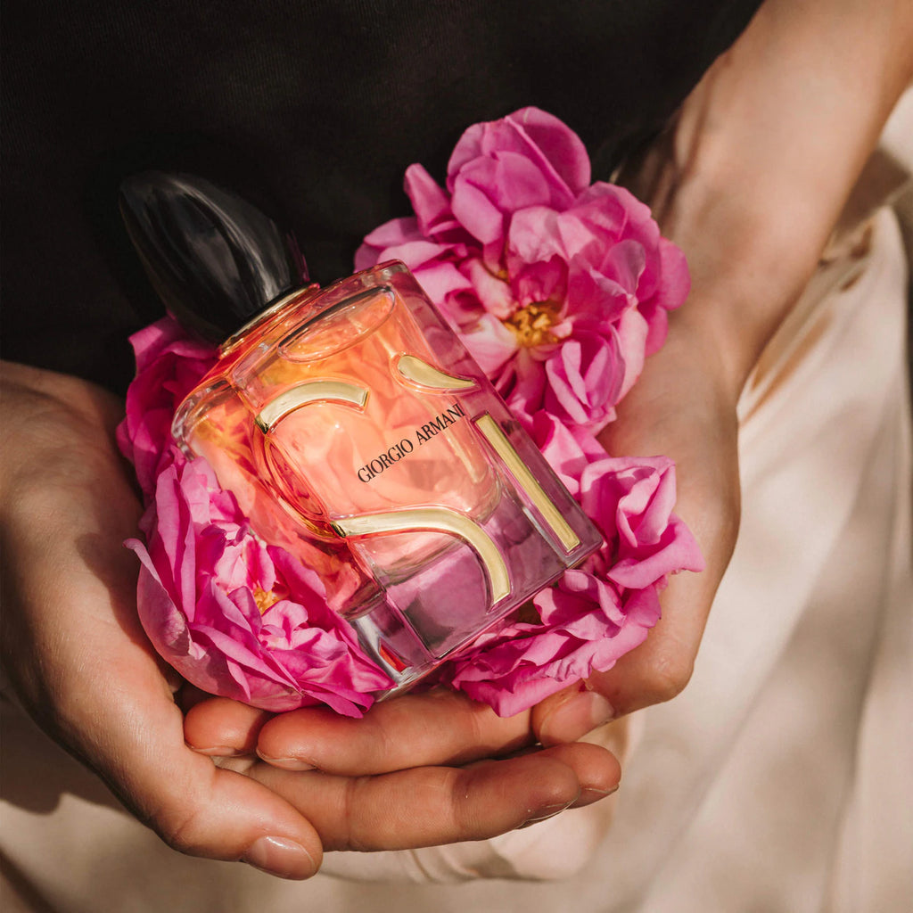 Person holding a Giorgio Armani perfume bottle with pink flowers
