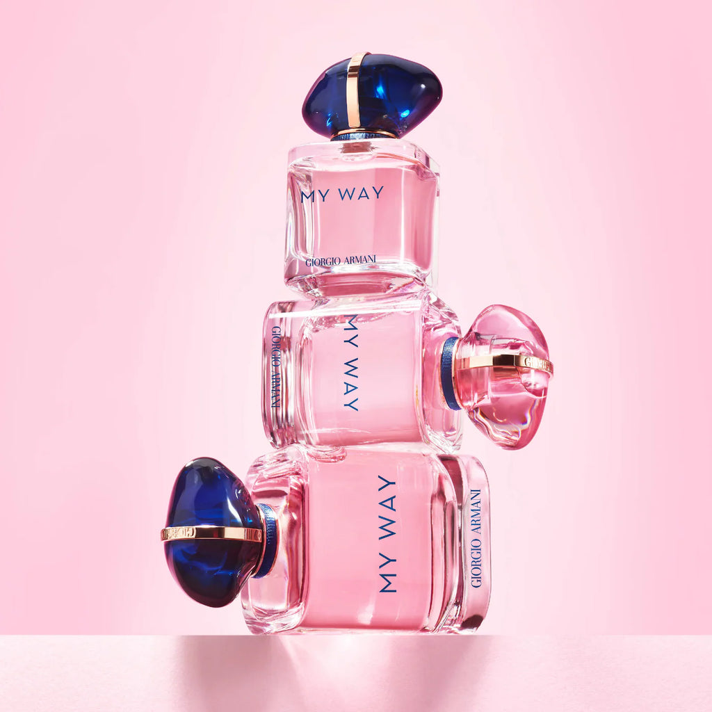 Pink Armani perfume bottles with blue caps on a pink background