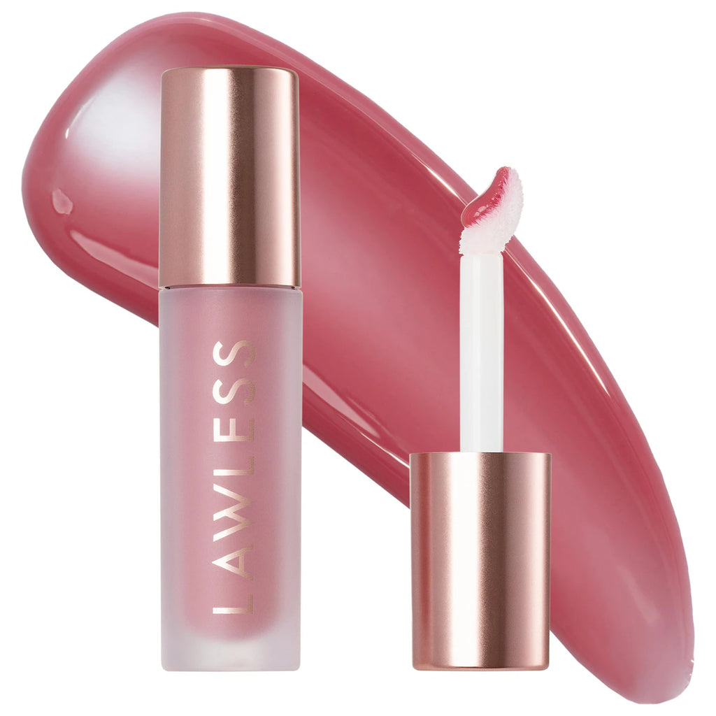 A frosted glass lip product tube with a rose gold cap stands next to its applicator wand, with a large glossy swatch of the pink lip color behind them on a white background. The brand name 'LAWLESS' is printed vertically on the tube.