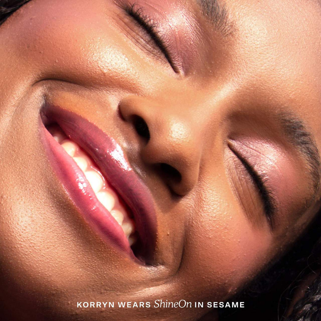 Close-up of a person's face with visible makeup, featuring the text 'KORRYN WEARS ShineOn IN SESAME'.