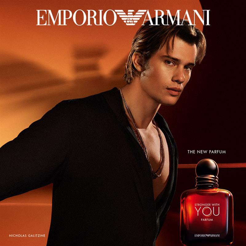 Advertisement for Emporio Armani perfume with a model and perfume bottle against an orange background