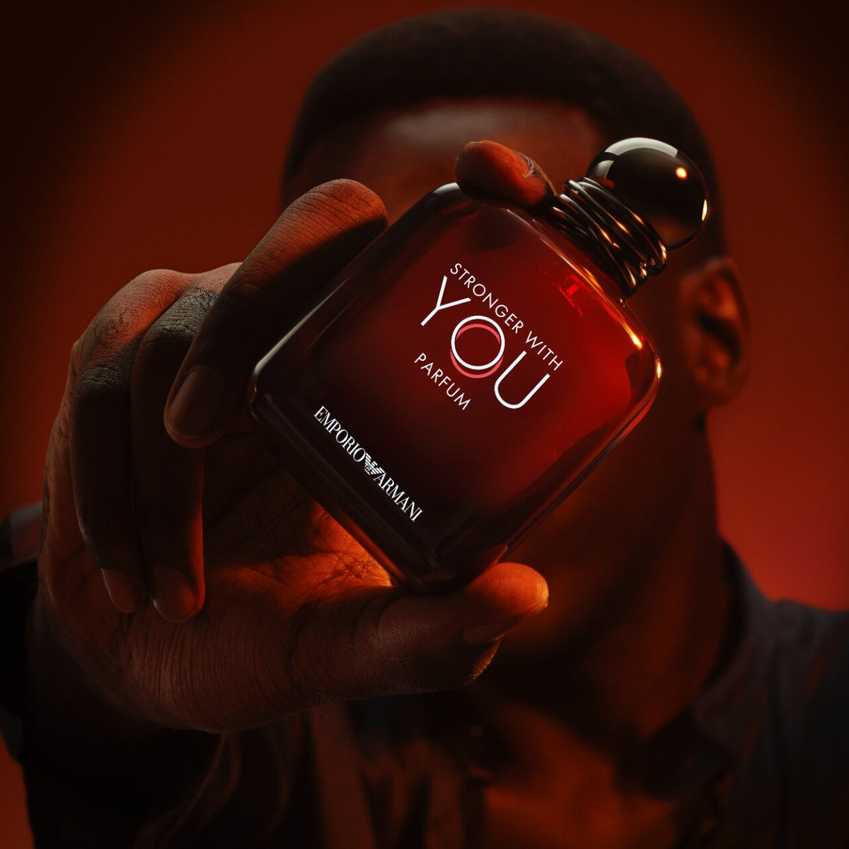 Person holding a bottle of Emporio Armani parfum with a dark background