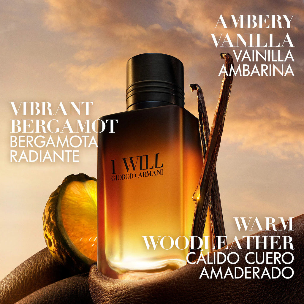 Giorgio Armani I Will fragrance bottle in amber glass with a black cap, styled with vanilla pods and citrus against a warm sunset sky, with Spanish scent names and English text overlays.