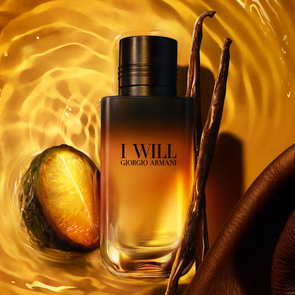 Giorgio Armani I Will fragrance bottle with amber liquid, set against a golden liquid background with vanilla beans and a citrus slice.