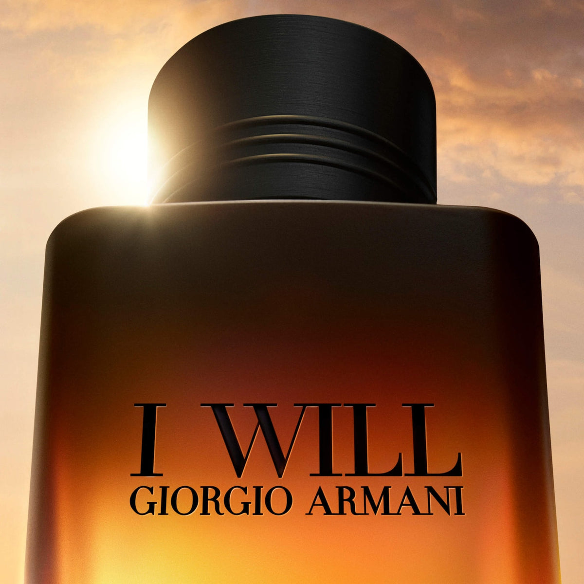 Giorgio Armani 'I Will' perfume bottle with a black cap and amber-brown gradient bottle, set against a dramatic sunset sky background.