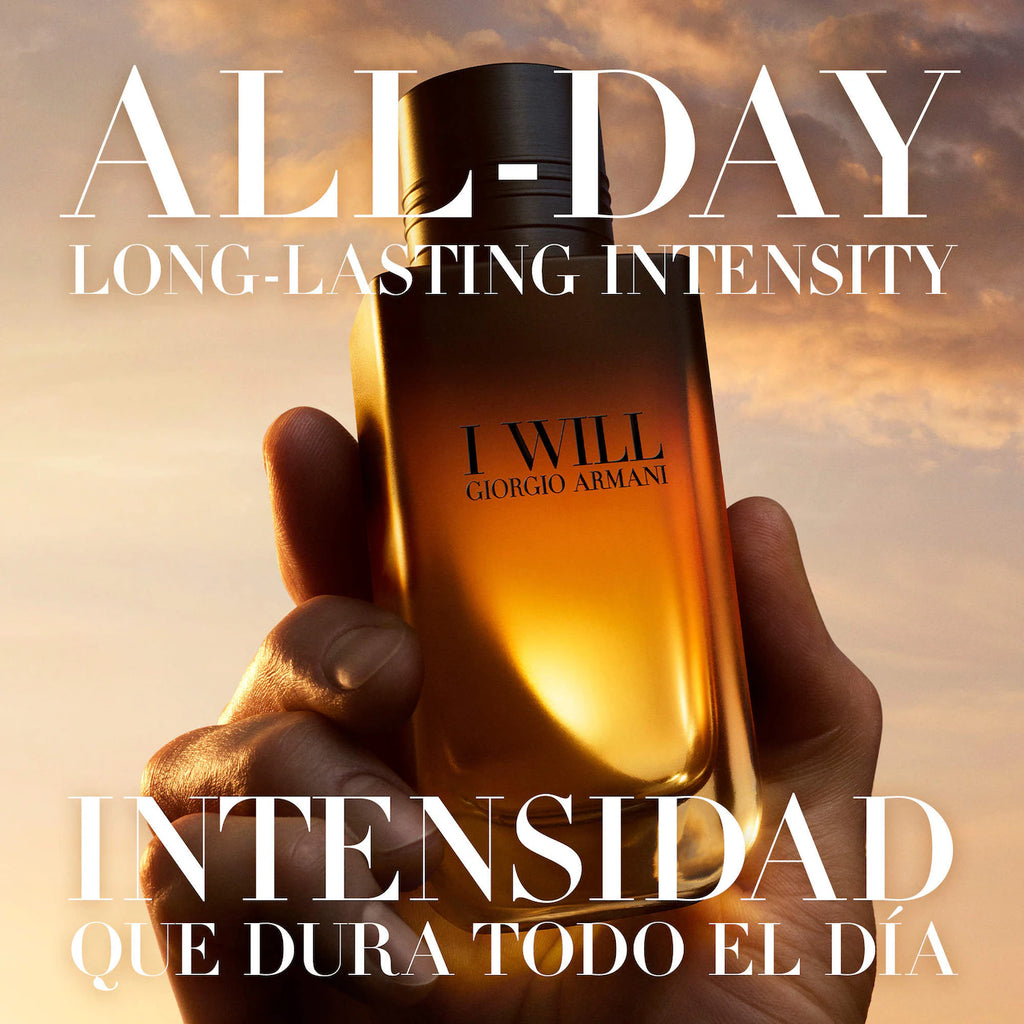 A hand holds a Giorgio Armani I Will fragrance bottle against a warm golden sky background, with large Spanish text reading 'ALL-DAY LONG-LASTING INTENSITY' and 'INTENSIDAD QUE DURA TODO EL DÍA'.