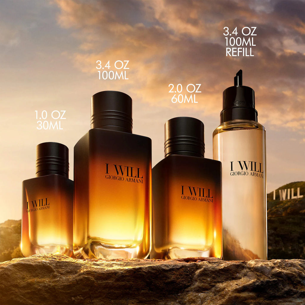 Four Giorgio Armani 'I Will' fragrance bottles and a refill bottle displayed outdoors on a rock at sunset, with text labels showing volumes: 1.0 oz 30ml, 3.